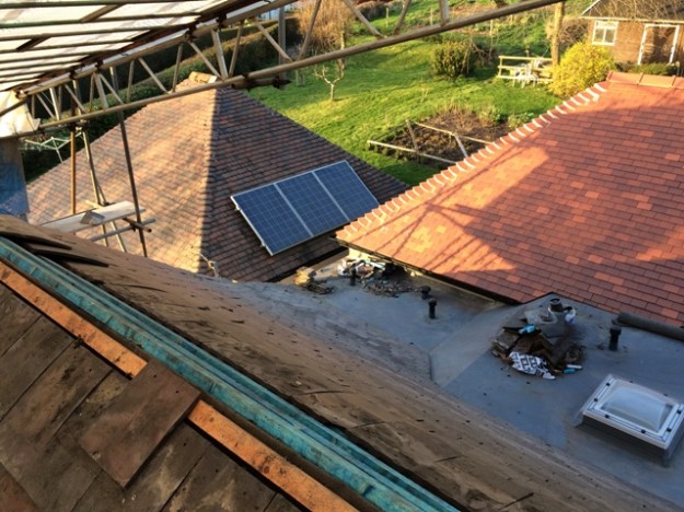 Newly tiled roof sloping down sharply to flat roof over utility, not quite completed